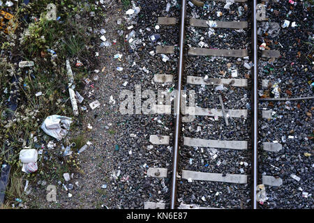 Der Blick von oben auf ein gleisbett mit Schienen und Schotter Steine und viel Müll und Abfall. Stockfoto