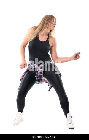 Blonde junge Frau tanzen Dancehall Aerobic und bewegliche Arme weg suchen. Vorderansicht. Voller Körper Länge Porträt auf weißem Hintergrund. Stockfoto