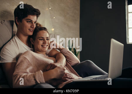 Hygge Paar mit Laptop auf dem Bett. Mann und Frau genießen Sie die Wiedergabe von Videos auf dem Laptop beim Entspannen im Schlafzimmer. Stockfoto