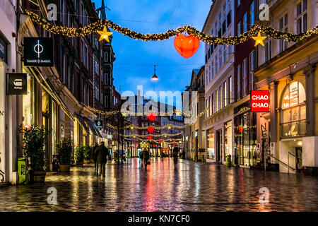 Weihnachtseinkaufsstraße in Kopenhagen mit einigen Leuten, die nachts spazieren gehen, geschmückt mit rot leuchtenden Herzen, Kobmagergade, Dänemark, 5. Dezember 2013 Stockfoto