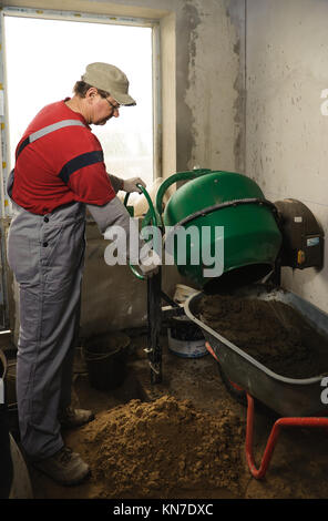 Betonboden. Mann woker setzt eine fertige Lösung in einer Schubkarre Stockfoto