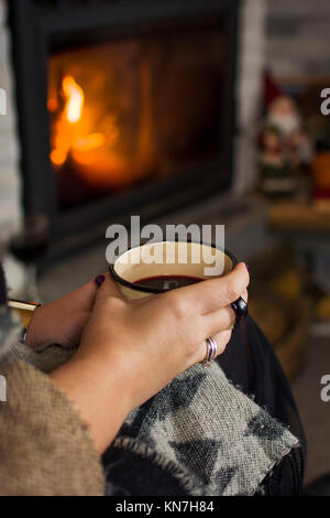 Frau trinkt Glühwein am Kamin, winter Lifestyle Stockfoto