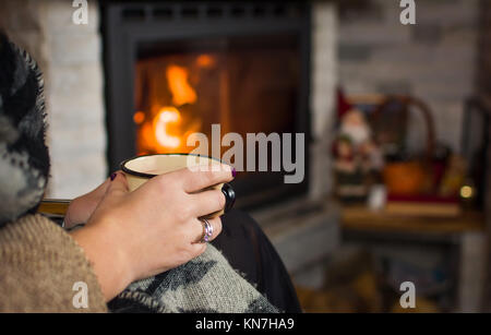 Frau trinkt Glühwein am Kamin, winter Lifestyle Stockfoto