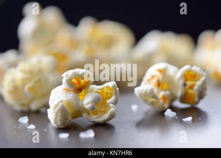 Popcorn und Salz auf schwarzem Hintergrund isoliert.