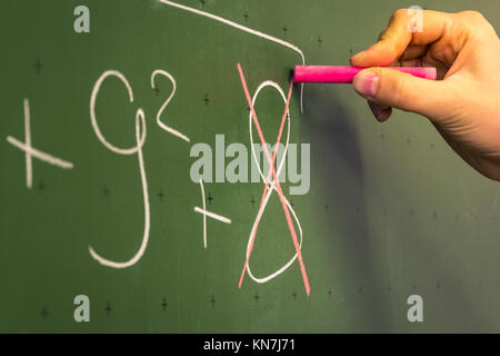 Weibliche Hand Lehrer Schreiben auf grüner Tafel Professor Universität weißer Kreide Hochschulbildung Lektion Mathe Nummer falsch Stockfoto