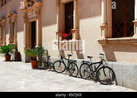 Abgestellte Fahrräder in der Nähe von einem schönen Gebäude in Alcudia, Spanien Stockfoto