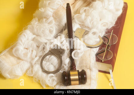 Für Richter: Richter Perücke, handclufs, Richter Hammer, Buch Ende Brillen auf gelbem Hintergrund Stockfoto