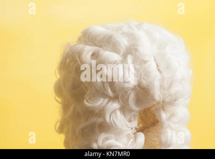 Perücke auf gelbem Hintergrund beurteilen. Stockfoto