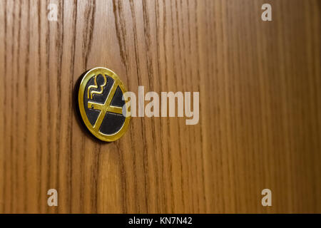 Golden Metal No Smoking Sign auf braunen Holztür Hotel Stockfoto