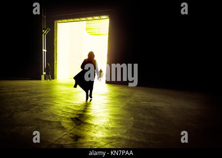 Silhouette einer Frau, die zu Fuß in die beleuchtete, großes Zimmer, Milano, Italien Stockfoto