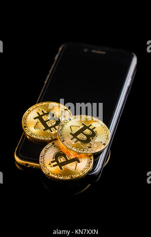 Bitcoin liegt auf einem Smartphone auf schwarzem Hintergrund. Stockfoto