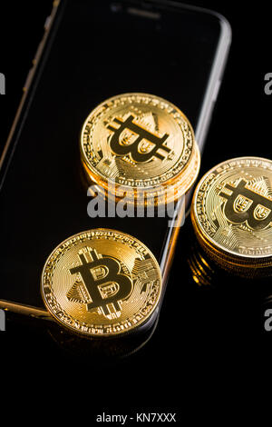 Bitcoin liegt auf einem Smartphone auf schwarzem Hintergrund. Stockfoto