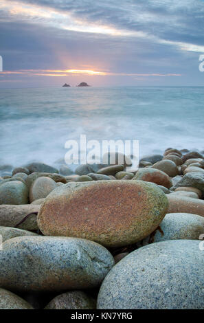 West Cornwall Meer bei Sonnenuntergang mit bewegtem Wasser rollen über große Beach Pebbles Stockfoto