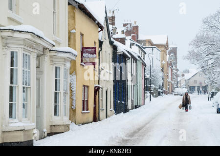 Presteigne, Powys, Wales, UK. 10. Dezember 2017. Ein starker Schneefall deckt viel von Wales einschließlich dieser kleinen walisischen Stadt. Ein shopper macht Ihren Weg nach unten die verschneite Hauptstraße. Kredit Alex Ramsay/Alamy leben Nachrichten Stockfoto