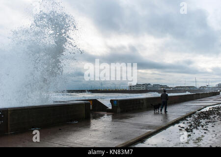 Brighton, East Sussex. 10. Dezember 2017. UK Wetter. Fußgänger, die am späten Nachmittag einen Spaziergang dodge riesige Wellen, die auf den Spencer Court entfernt in der Nähe von Brighton Marina nach einem Tag des eiskalten Wetter, starke Winde und Regen. Credit: Francesca Moore/Alamy leben Nachrichten Stockfoto