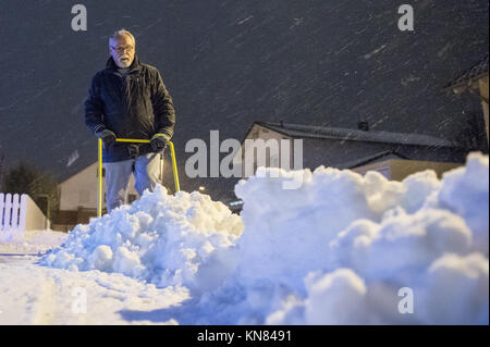 Straubing, Deutschland. 10 Dez, 2017. Ein Mann schaufeln Schnee vom Bürgersteig am Abend in Straubing, Deutschland, 10. Dezember 2017. Foto: Armin Weigel/dpa/Alamy leben Nachrichten Stockfoto