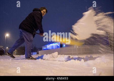 Straubing, Deutschland. 10 Dez, 2017. Eine Frau schaufeln Schnee vom Bürgersteig am Abend in Straubing, Deutschland, 10. Dezember 2017. Foto: Armin Weigel/dpa/Alamy leben Nachrichten Stockfoto