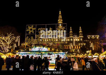 Wien, Österreich, 10. Dezember 2017. Beleuchtete Frohe Weihnachten (Frohe Weihnachten) Schild am Eingang zum traditionellen festlichen Jahreszeit Wiener Weihnachtsmarkt im Stadtpark (Christkindlmarkt am Rathausplatz, Wiener Christkindlmarkt), der größten weihnachtlichen Markt in Wien, befindet sich das Neue Rathaus (Neues Rathaus) im Museum im Zentrum von Wien (Innere Stadt). Credit: Graham Prentice/Alamy Leben Nachrichten. Stockfoto