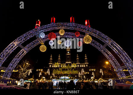 Wien, Österreich, 10. Dezember 2017. Beleuchteter Eingang arch und Frohe Weihnachten (Frohe Weihnachten) an der traditionellen festlichen Jahreszeit Wiener Weihnachtsmarkt im Stadtpark (Christkindlmarkt am Rathausplatz, Wiener Christkindlmarkt), der größten weihnachtlichen Markt in Wien, befindet sich das Neue Rathaus (Neues Rathaus) im Museum im Zentrum von Wien (Innere Stadt). Credit: Graham Prentice/Alamy Leben Nachrichten. Stockfoto