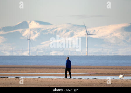 Southport, Merseyside. 11. Dezember 2017. UK Wetter. Sonnig in Southport. Hund Spaziergänger trotzen dem eisigen Temperaturen auf Ihre geliebten Haustiere nehmen für einen auf dem gefrorenen Sand Strand in Southport, Merseyside schlendern. Clear Skies erstellt einige einen atemberaubenden Blick über die schneebedeckten Berge von North Wales im Westen und den Cumbrian Fells im Norden. Credit: cernan Elias/Alamy leben Nachrichten Stockfoto