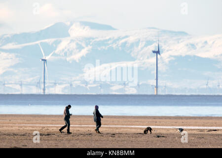 Southport, Merseyside. 11. Dezember 2017. UK Wetter. Sonnig in Southport. Hund Spaziergänger trotzen dem eisigen Temperaturen auf Ihre geliebten Haustiere nehmen für einen auf dem gefrorenen Sand Strand in Southport, Merseyside schlendern. Clear Skies erstellt einige einen atemberaubenden Blick über die schneebedeckten Berge von North Wales im Westen und den Cumbrian Fells im Norden. Credit: cernan Elias/Alamy leben Nachrichten Stockfoto