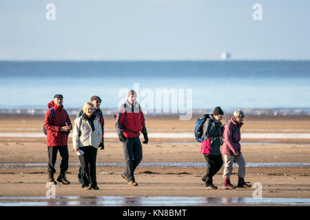 Southport, Merseyside. 11. Dezember 2017. UK Wetter. Sonnig in Southport. Eine Gruppe von Wanderern trotzen dem eisigen Temperaturen zu einem auf dem gefrorenen Sand Strand in Southport, Merseyside schlendern. Clear Skies erstellt einige einen atemberaubenden Blick über die schneebedeckten Berge von North Wales im Westen und den Cumbrian Fells im Norden. Credit: cernan Elias/Alamy leben Nachrichten Stockfoto