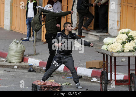 Dezember 11, 2017 - Hebron, West Bank, Palästina - palästinensische Demonstranten werfen Steine gegen israelische secrity Kräfte während der Auseinandersetzungen hinter einem Checkpoint im Zentrum der Stadt von der West Bank Stadt Hebron am 11. Dezember 2017, wie Demonstrationen weiterhin im Nahen Osten und anderswo über uns Präsident Donald Trump Erklärung von Jerusalem als Hauptstadt Israels zu Flare (Credit Bild: © Wisam Hashlamoun/APA Bilder über ZUMA Draht) Stockfoto