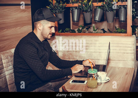 Glücklich, junger Mann mit Laptop Computer Musik hören und Surfen im Internet im Cafe Bar Stockfoto
