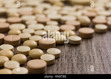 Haufen sortierte beige Kapseln auf Holztisch. Stockfoto