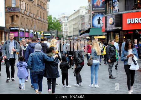 Junge islamische Mädchen mit Hijabed Mutter drehen Kopf an junge asiatische Frau in westlicher Kleidung zu suchen, Leicester Square, London, England, Großbritannien Stockfoto