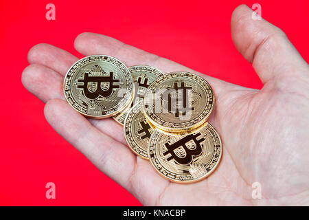 Goldmünzen der elektronischen crypto Währung Bitcoin, in bar in menschlichen Palm liegen, Nahaufnahme, roten Hintergrund. Stockfoto