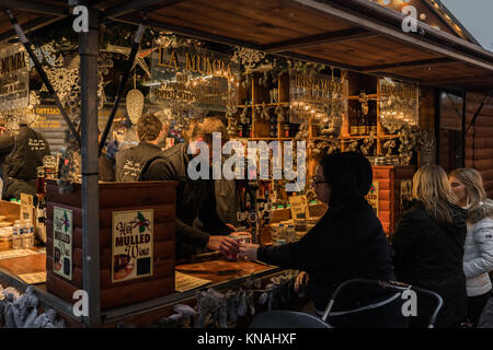 Marktstand Händler servieren Speisen und Getränke für Kunden an der Manchester Weihnachtsmärkte Rund um die City, Manchester, England, Großbritannien Stockfoto