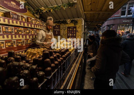 Marktstand Händler servieren Speisen und Getränke für Kunden an der Manchester Weihnachtsmärkte Rund um die City, Manchester, England, Großbritannien Stockfoto