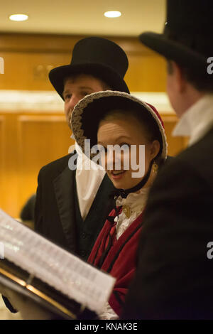 Singen Gruppe von Menschen in traditionellen Kostümen Weihnachtslieder im Fairmont Olympic Hotel in Seattle, Washington Stockfoto