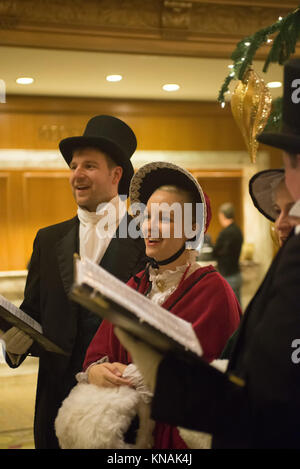 Singen Gruppe von Menschen in traditionellen Kostümen Weihnachtslieder im Fairmont Olympic Hotel in Seattle, Washington Stockfoto