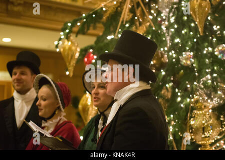 Singen Gruppe von Menschen in traditionellen Kostümen Weihnachtslieder im Fairmont Olympic Hotel in Seattle, Washington Stockfoto