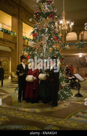 Singen Gruppe von Menschen in traditionellen Kostümen Weihnachtslieder im Fairmont Olympic Hotel in Seattle, Washington Stockfoto