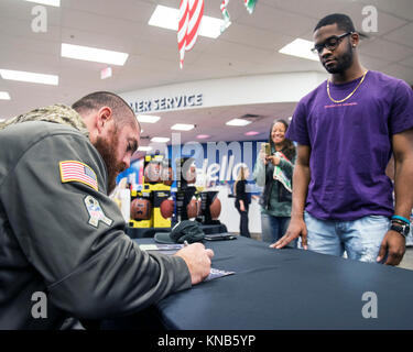 Oakland Raiders tight end Lee Smith Zeichen ein Autogramm für einen Lüfter bei einem Besuch des Travis Air Force Base, Calif., Exchange, Dez. 5, 2017. Smith hat sieben Spielzeiten in der NFL mit den Oakland Raiders und Buffalo Bills gespielt. Smith hat eine große Anerkennung für die Männer und Frauen dienen, denn es ermöglicht ihm zu spielen ein Spiel, das er liebt und ihn und seine Familie sicher halten. (U.S. Air Force Stockfoto