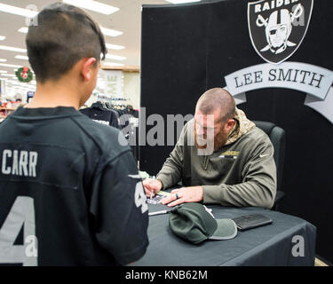 Oakland Raiders tight end Lee Smith Zeichen ein Autogramm für einen Lüfter bei einem Besuch des Travis Air Force Base, Calif., Exchange, Dez. 5, 2017. Smith hat sieben Spielzeiten in der NFL mit den Oakland Raiders und Buffalo Bills gespielt. Smith hat eine große Anerkennung für die Männer und Frauen dienen, denn es ermöglicht ihm zu spielen ein Spiel, das er liebt und ihn und seine Familie sicher halten. (U.S. Air Force Stockfoto