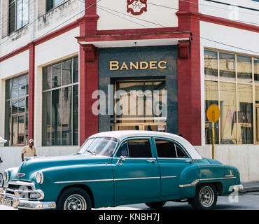 Holguín Kuba - August 2017: Klassische Oldtimer vor der Bank fahren mit Apple Aufkleber am Fenster. Stockfoto