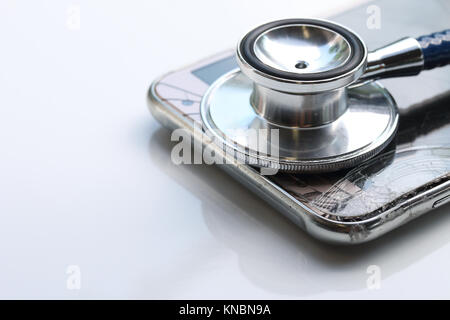 Telefon mit einem defekten Bildschirm mit Stethoskop, Handy Reparatur Konzept Stockfoto