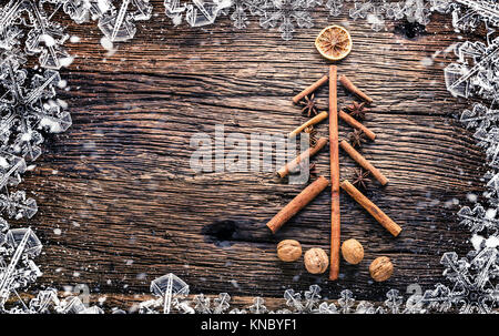 Weihnachtsbaum aus Zimt, Sternanis und Walnüsse auf rustich Holztisch. Abstrakte snowy Rahmen. Stockfoto