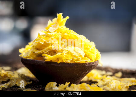 Zea mays Mais, Flocken in einem Ton Schüssel auf eine gunny Hintergrund. Stockfoto