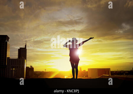 Silhouette einer Frau die Hände auf das Gebäude bei Sonnenuntergang Stockfoto