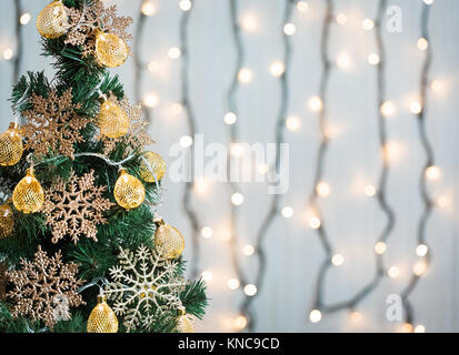 Ein Weihnachtsbaum mit Schneeflocken und eine Girlande auf dem Hintergrund einer Bokeh und White boards eingerichtet. Frohe Weihnachten, Ideen für Postkarten für Winte Stockfoto