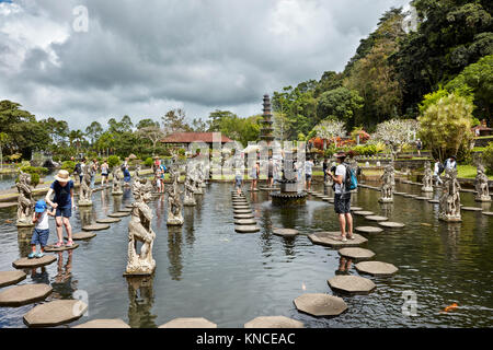 Touristen zu Fuß auf Trittsteinen in Tirta Gangga Wasserpalast, ein ehemaliger königlicher Palast. Karangasem Regentschaft, Bali, Indonesien. Stockfoto