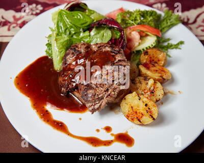 Gegrilltes sirloin Rindersteak mit Kartoffelecken und grünem Salat in einem lokalen Warung (kleines Restaurant) serviert. Bali, Indonesien. Stockfoto