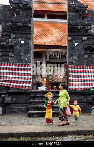 Frau mit Kindern tragen traditionelle balinesische Kleidung gehen Sie zu einem örtlichen Tempel in der Nähe von Bugbug Dorf. Karangasem Regency, Bali, Indonesien. Stockfoto