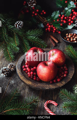 Rote Äpfel, Preiselbeeren und Fir Tree Branches. Weihnachten noch leben. Winter wallpaper. Vertikale Zusammensetzung Stockfoto