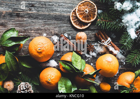Traditionelle Weihnachten Hintergrund mit Tannenbaum, Mandarinen, Zimt und natürlichen Schnee auf Holz- Hintergrund. Ansicht von oben, getönten Bild Stockfoto